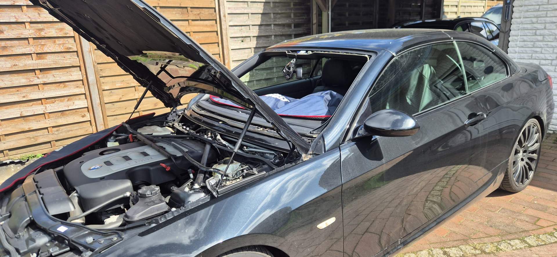 Offener Motorraum eines BMW beim Windschutzscheibenwechsel